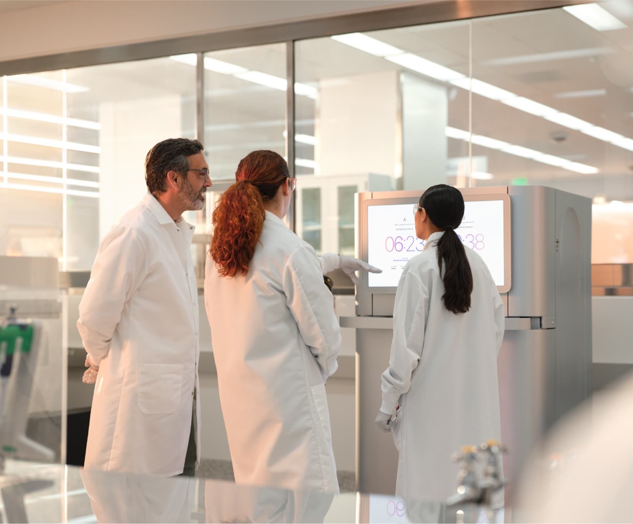 Back view of a three scientists looking at the dual run configuration on the touch screen of the NovaSeq X.